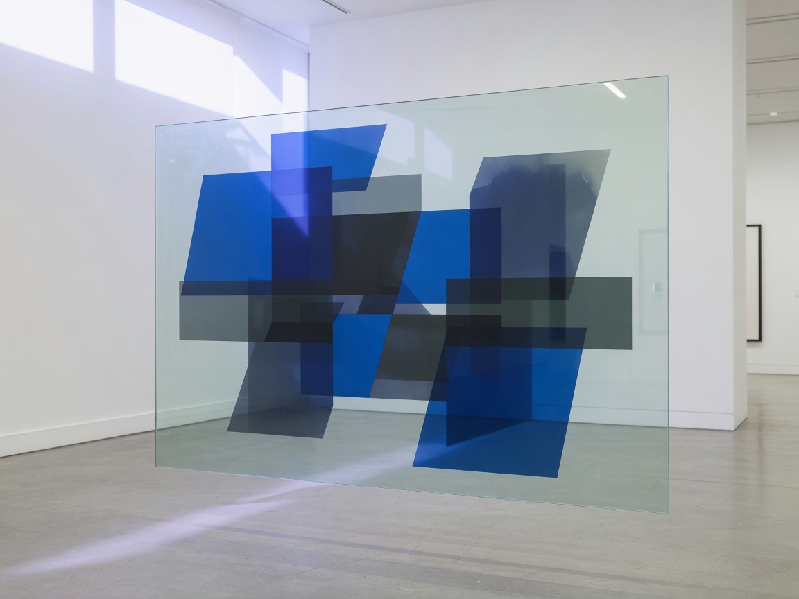 A floating glass panel of cobalt and charcoal geometry in a bright gallery.
